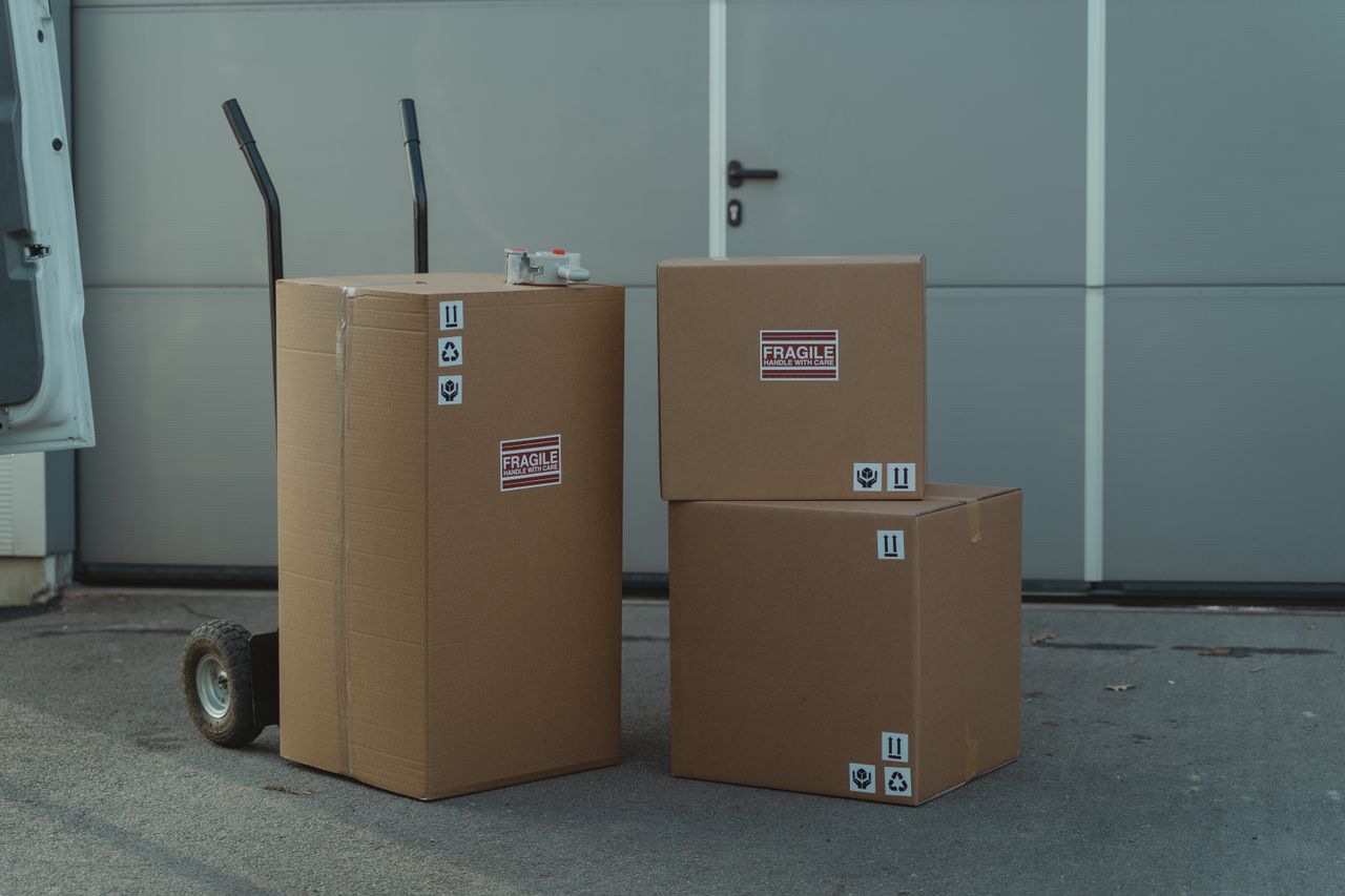 about-01 Three cardboard boxes on a dolly, ready for shipping outside a warehouse.